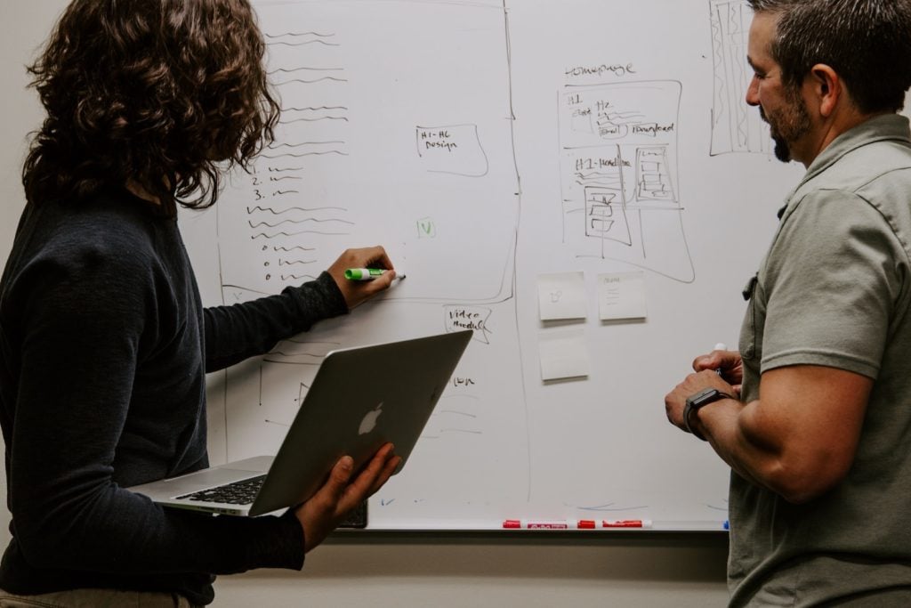 Two professionals writing on whiteboard